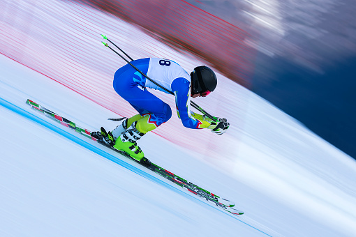 Side view of young male skier at straight downhill race, panning
