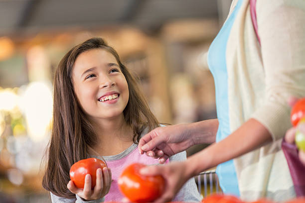 dziecko w wieku szkoły podstawowej dziewczynka uśmiechając się podczas zakupów z matka - farmers market agricultural fair vegetable child zdjęcia i obrazy z banku zdjęć