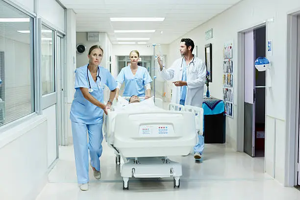 Doctor and nurses rushing patient on gurney in hospital corridor