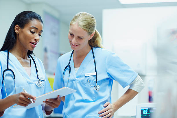 Nurses discussing over documents in hospital Young female nurses discussing over medical documents in hospital nurse photos stock pictures, royalty-free photos & images