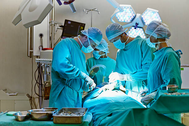 group of surgeons in operating room - operationssaal stock-fotos und bilder