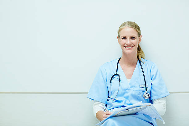 happy female nurse sitting in hospital - stethoscope blue healthcare and medicine occupation - fotografias e filmes do acervo