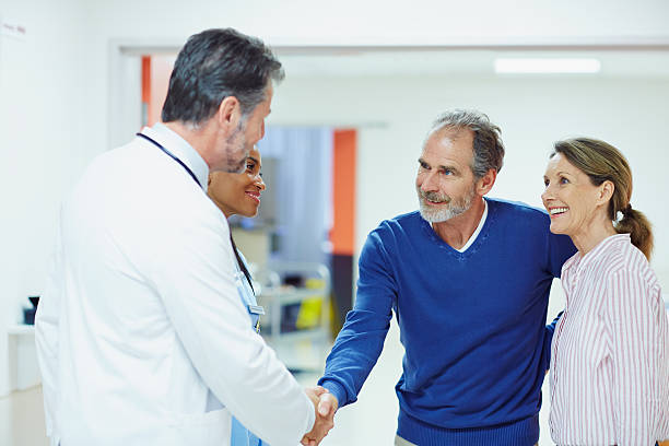 doctor greeting couple in hospital - doctor patient greeting talking imagens e fotografias de stock