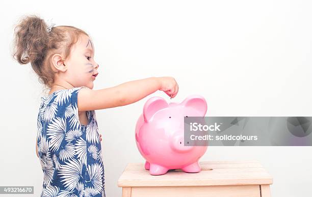 Little Girl Placing Coin In Piggy Bank Stock Photo - Download Image Now - Child, Piggy Bank, Back to School