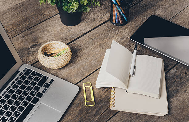 istock Notebook and laptop on old wooden desk 493217034