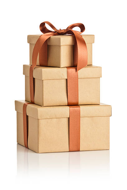 Brown gift box tied up with bow isolated on white Three gift boxes arranged in a pile, wrapped with brown craft paper and tied up with bronze colored ribbon bow sitting on reflective white background. DSRL studio photo taken with Canon EOS 5D Mk II and Canon EF 70-200mm f/2.8L IS II USM Telephoto Zoom Lens stacked presents stock pictures, royalty-free photos & images