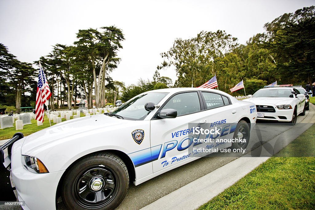 US Memorial Day Ceremony, Police cars parked on the Cemetery San Francisco, USA - May 27, 2013: US Memorial Day Ceremony, The Presidio National Cemetery, San Francisco. Veterans and citizens are attending the cemetery.  The Ceremony was also dedicated to the 60th Anniversary of Korean War (1950-1953) remembering and honoring more than 50.000 Americans killed during that war. Police cars  are parked along the Cemetery during ceremony. Cemetery is decorated with many American flags. Adult Stock Photo