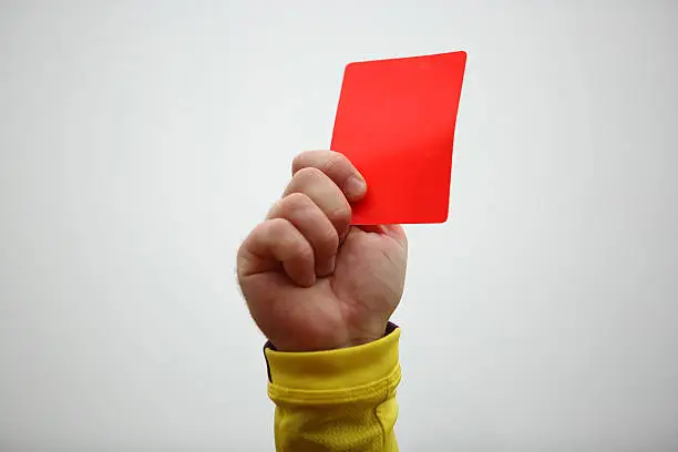 Hand of football referee holding up red card