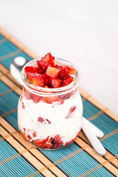 Stock photo showing a close-up studio shot of a glasses containing layered, strawberry mousse desserts topped with whole strawberries.
