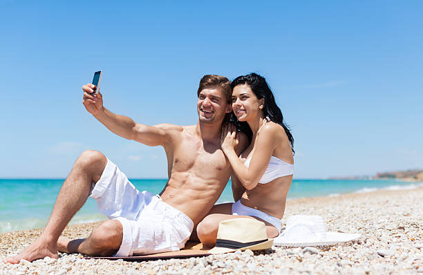 istock couple on beach taking self photo with phone 493222253