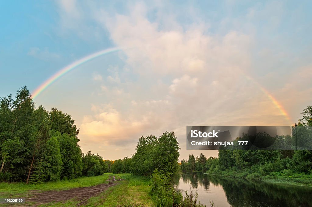 Beautiful rainbow over river with dirty road along Beautiful rainbow over river with dirty road along. Arkhangelsky region, Russia. Beauty In Nature Stock Photo