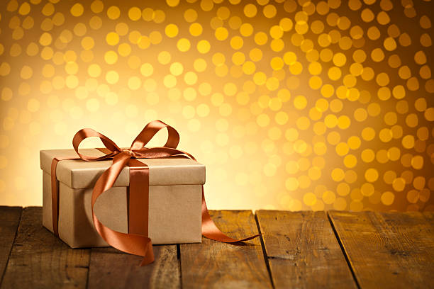 istock Brown gift box on wood table against golden bokeh lights 493237730