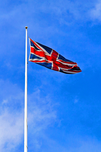 The national flag of United Kingdom, Europe floating in the wind over blue sky