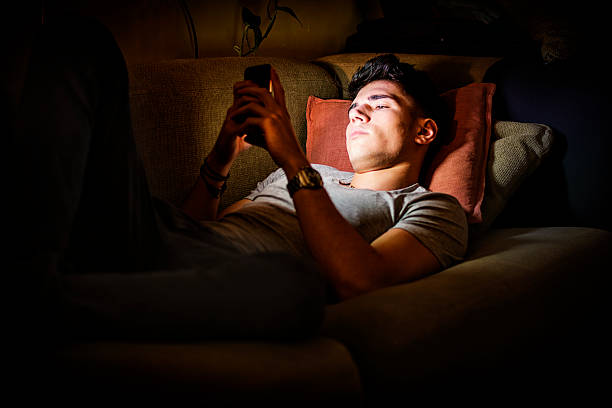 istock Young Man on Sofa Lit by Light from Cell Phone 493240008