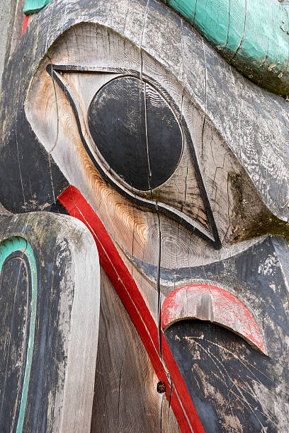 Totem Close Up A close up of a weathered totem decorated with some red and green paint. haida gwaii totem poles stock pictures, royalty-free photos & images