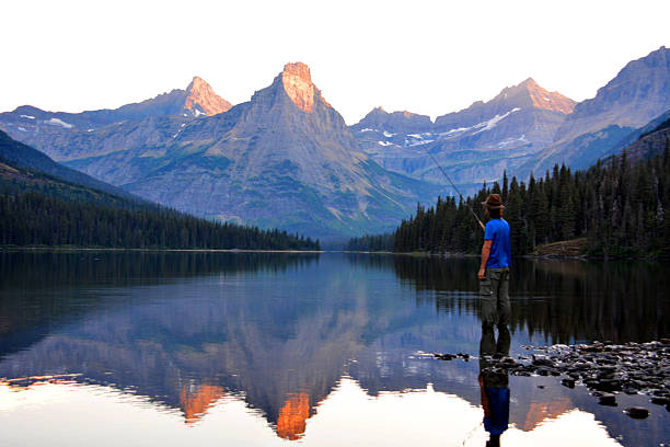 A man fly fishes in Montana among the mountians.