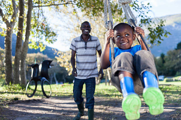 istock African boy being pushed on a swing by his father 493244109