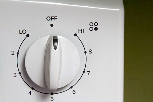 White knob on an electric oven that shows the temperature setting.  Off is the vertical knob position.  Low is on the left and the knob rotates through settings numbered 2 through 9 until you reach high.  The knob is for the front right burner.