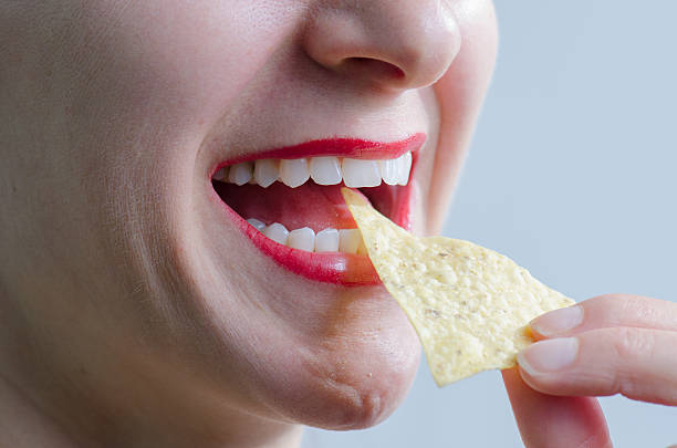 istock Close up on woman eating a chip 493247882