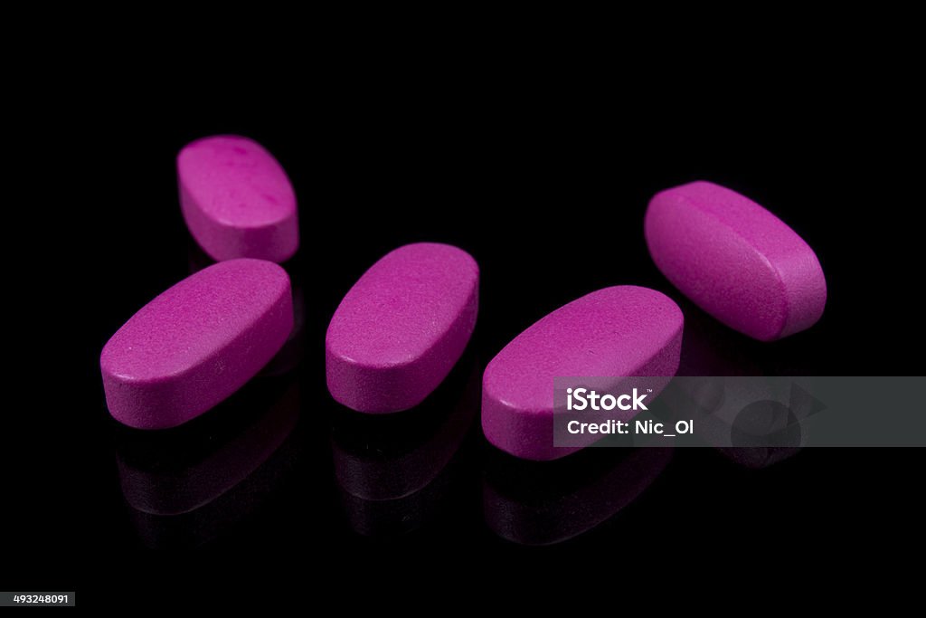 Rosa pillole vitamine su sfondo nero - Foto stock royalty-free di Accudire