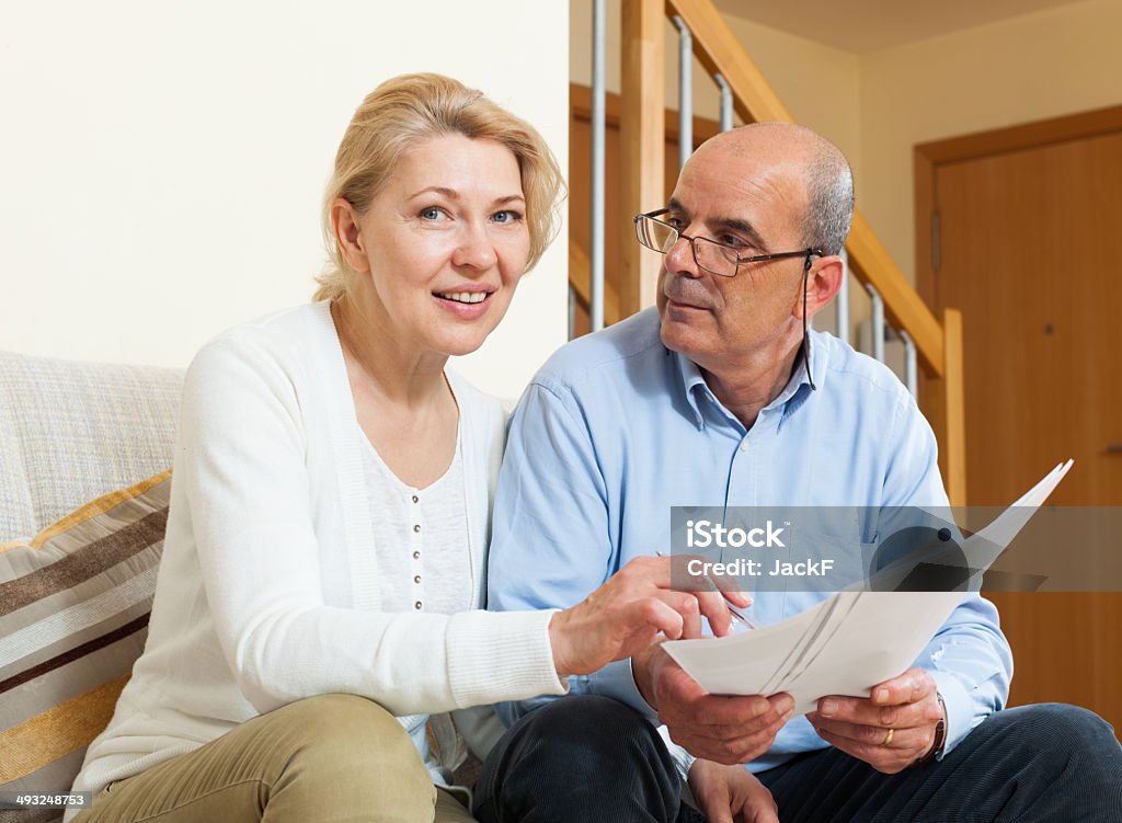 Mature couple with documents at home Smiling senior mature couple with financial documents on sofa 60-69 Years Stock Photo