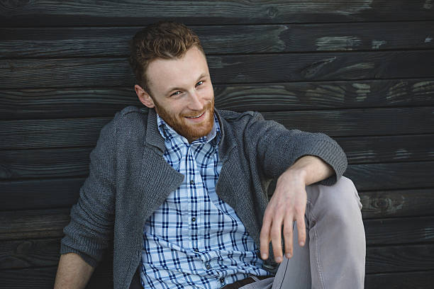 istock Handsome young man sitting on the wooden floor 493250815
