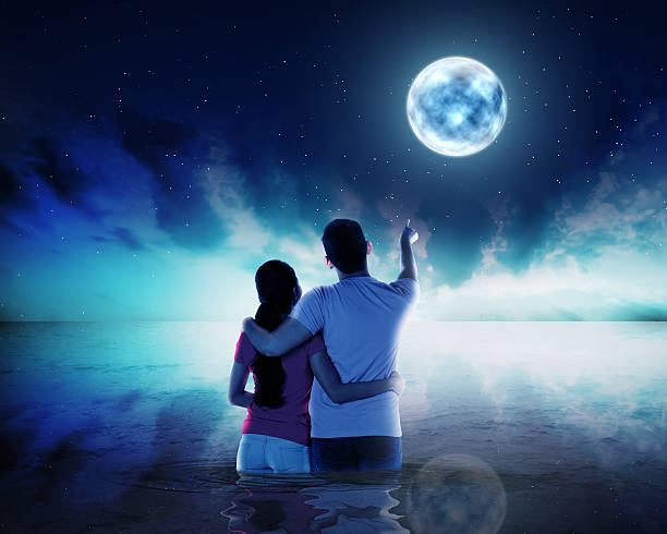 istock Young couple ponting moon at night time 493270236