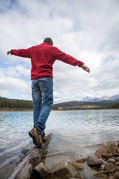 istock Man walking on a tree log on the lake 493270680