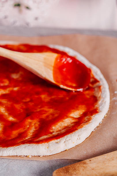 istock Spreading tomato sauce over pizza dough 493272608