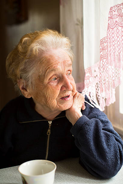 istock An elderly lady sitting near the window in the kitchen. 493276250
