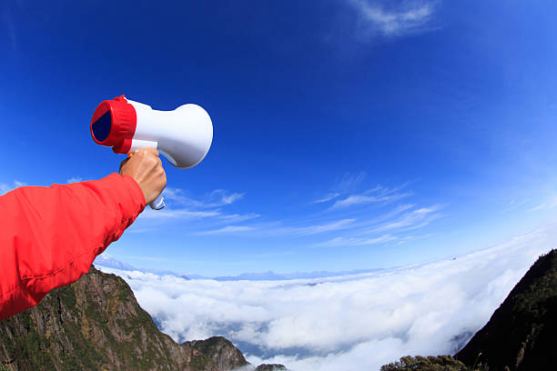 istock people hand hold loudspeaker to blue sky on mountain peak 493278174