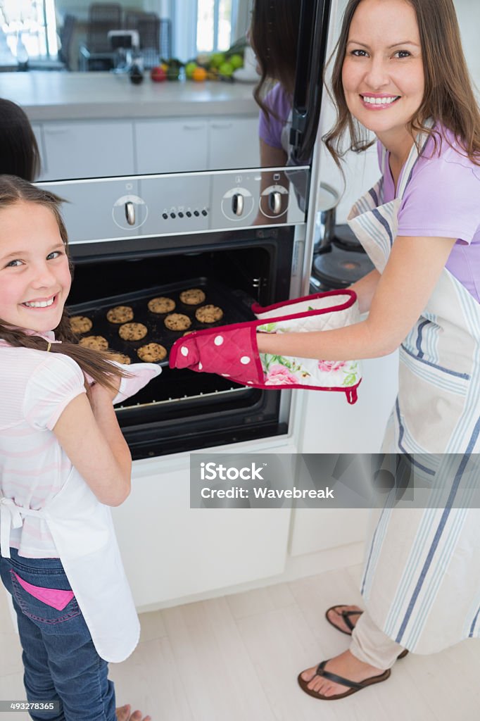 Smiling girl helping her mother prepare cookies in kitchen Portrait of a smiling young girl helping her mother prepare cookies in the kitchen at home 10-11 Years Stock Photo