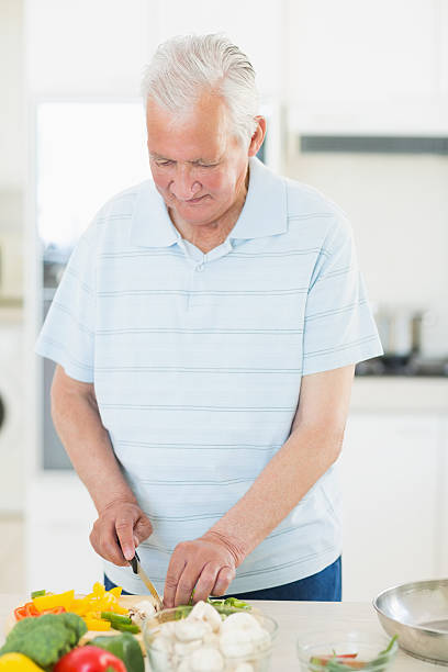 istock Senior man chopping vegetables in kitchen 493278385