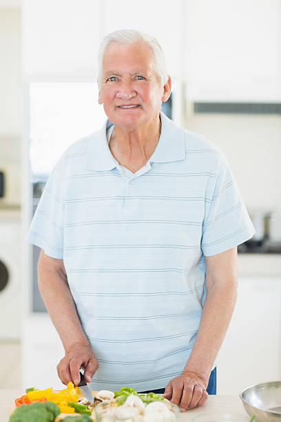 istock Smiling senior man chopping vegetables in kitchen 493278387