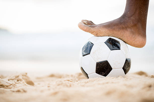 Classic black and white football soccer ball sits on sand beach
