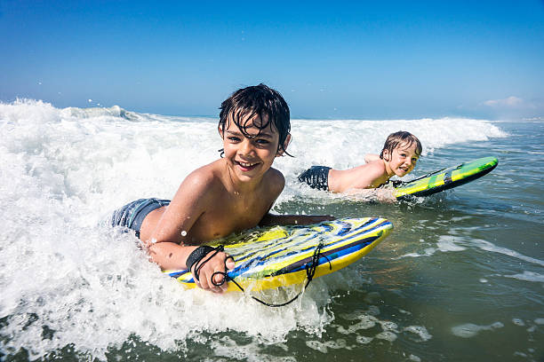 Brothers enjoying the surf on vacation stock photo