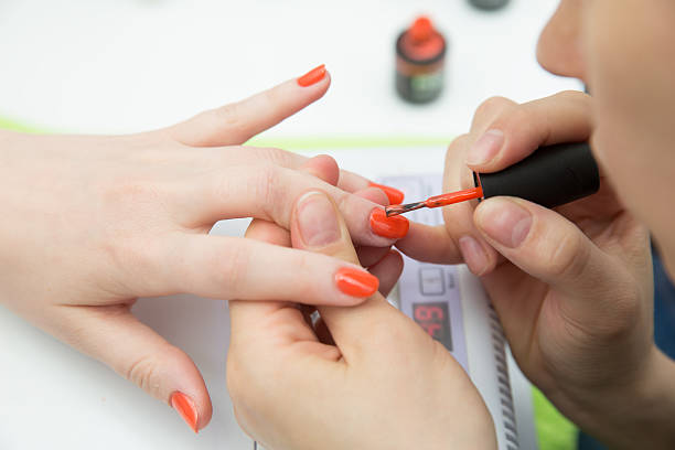 istock manicurists paints her nails painted orange 493279923