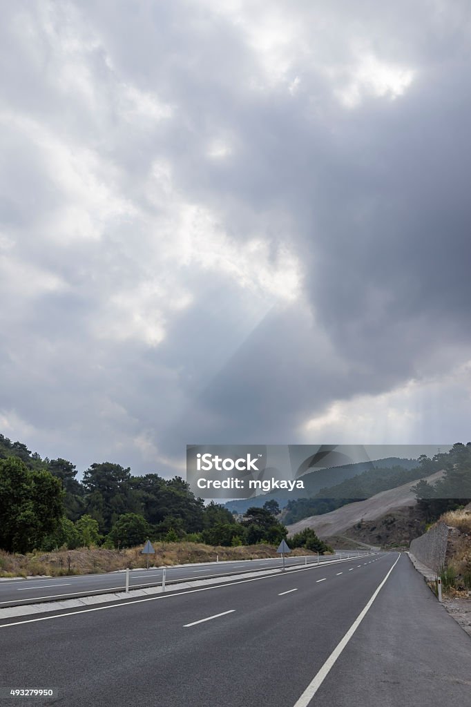 Highway with Heavy Sky Highway with cloudy sky, forest and mountainous landscape view background. 2015 Stock Photo
