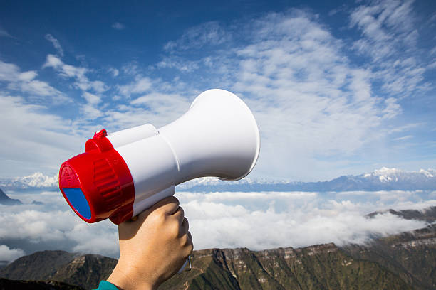 istock hand hold loudspeaker to blue sky on mountain peak 493281446