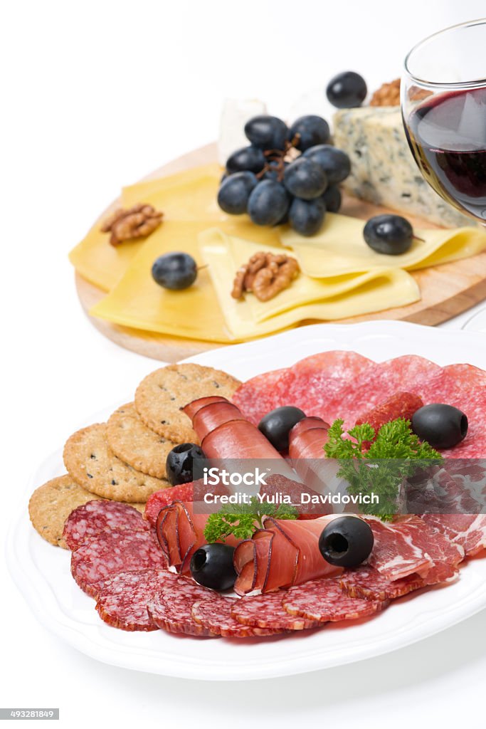 assorted deli meats, plate of cheese and red wine assorted deli meats, plate of cheese and a glass of wine, isolated on white Antipasto Stock Photo