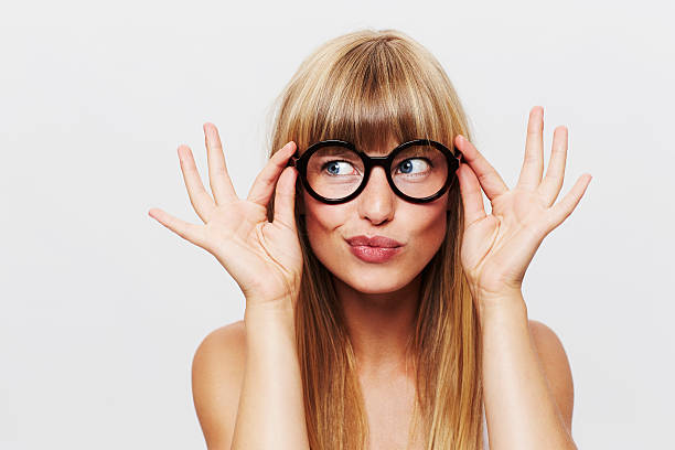 Beautiful woman adjusting spectacles in studio stock photo