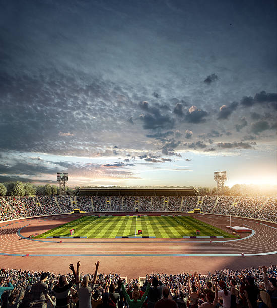 Dramatic . stadium with running tracks Outdoor floodlit stadium full of spectators under  evening sky and fog. Image made in 3D. image created 21st century blue architecture wide angle lens stock pictures, royalty-free photos & images