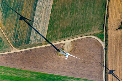 Aerial view on the windmill and his long shadow on the field