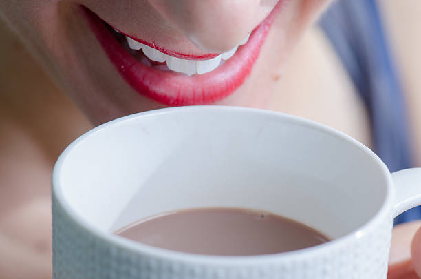 Close up of woman drinking in white cup , seen from front with white background