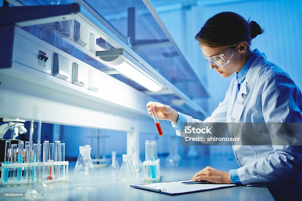 Testing substances Young woman working with liquids in glassware Laboratory Stock Photo