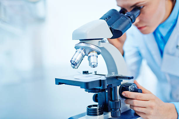 Scientific studies Young female chemist studying new substance in lab microscope stock pictures, royalty-free photos & images