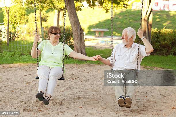 Senior Couple Swinging In The Park Stock Photo - Download Image Now - Senior Adult, Swinging, 2015