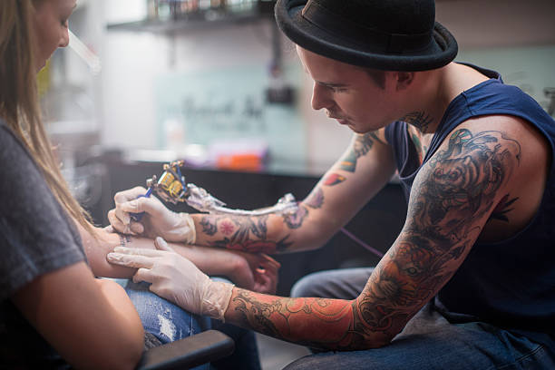 istock Artist making tattoo on customer's hand in studio 493307624