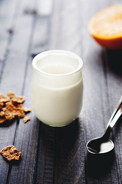 white yogurt with cornflakes and orange fruit on background 