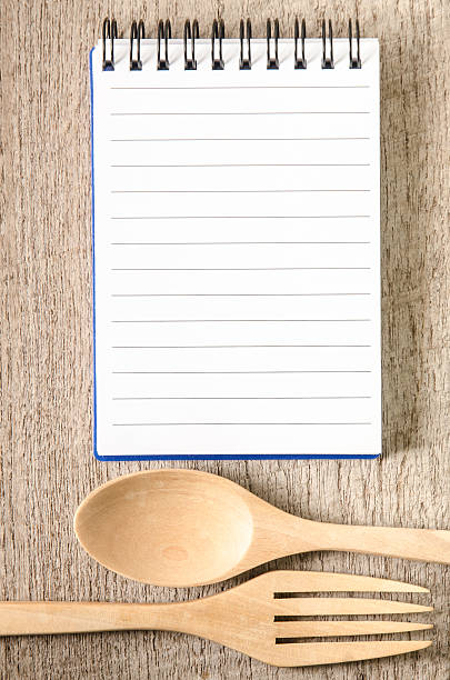istock Open cookbook and kitchenware on wooden background 493309076